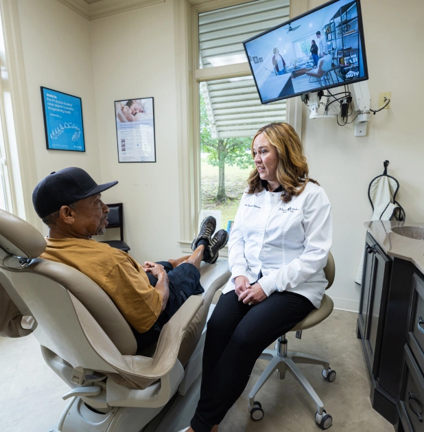 Dentist consulting with patient in modern dental office treatment room.