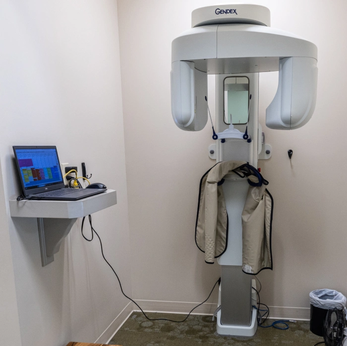 Dental panoramic X-ray machine with computer workstation in clinical treatment room.