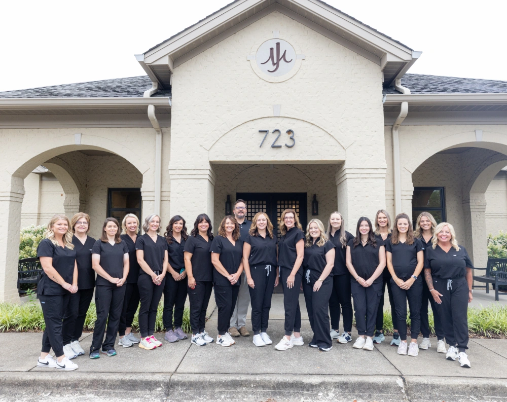Johnson and Mahan Dental Care team standing together in front of their dental office building.