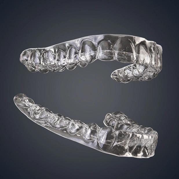 Clear dental aligners shown from upper and lower arch views against dark background.