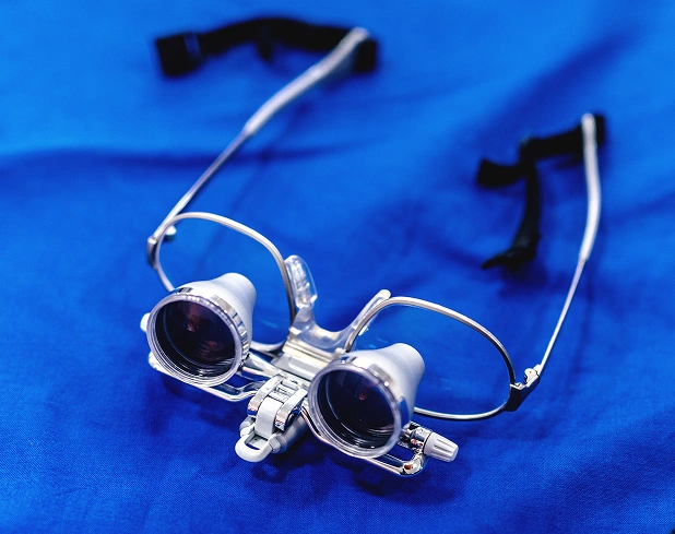 Dental loupes with magnification lenses on blue background for precision dental work