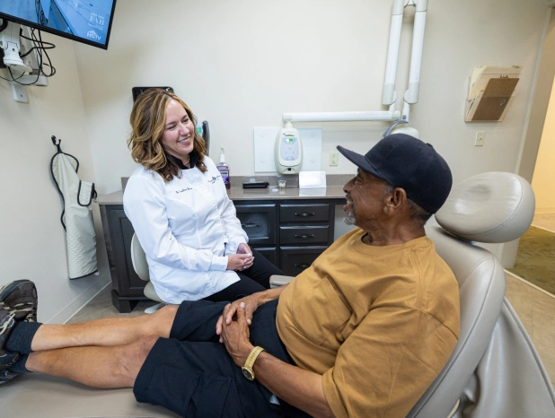 Female dental professional examining male patient in dental clinic treatment room.