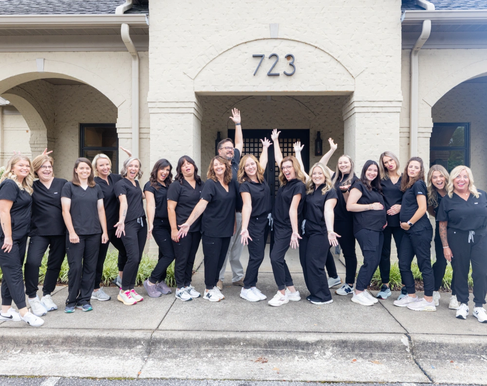Johnson and Mahan Dental Care team members in matching black shirts standing together outside their office building.